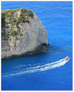 Auto cropped view of a cliff above the blue sea with a boat sailing along the coast